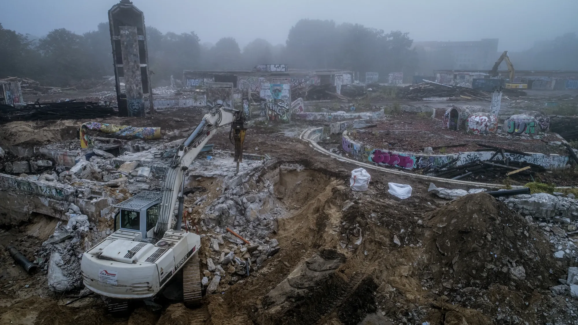 Stimmungsvolle Luftaufnahme einer Abbruch-Baustelle mit Bagger im Morgennebel