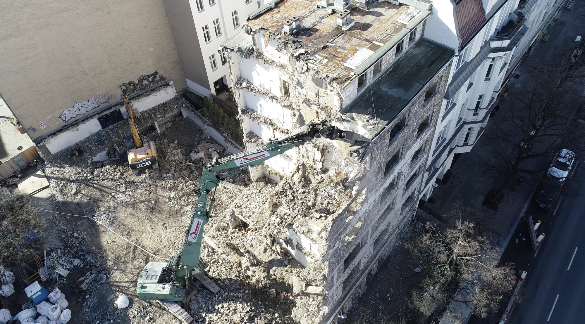 Longfront-Bagger beim geschossweisen Rückbau eines Altbaus in Berlin, Luftaufnahme