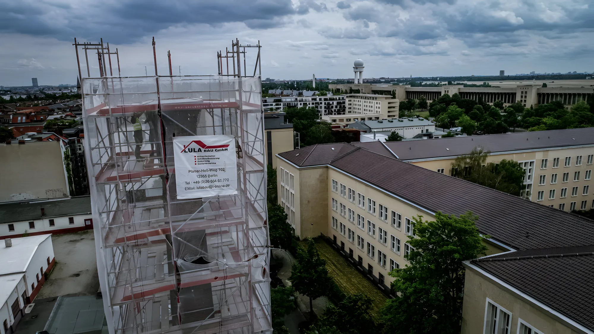 Eingerüsteter Gebäudeteil mit Lula-Bau Banner über den Dächern Berlins, Luftaufnahme